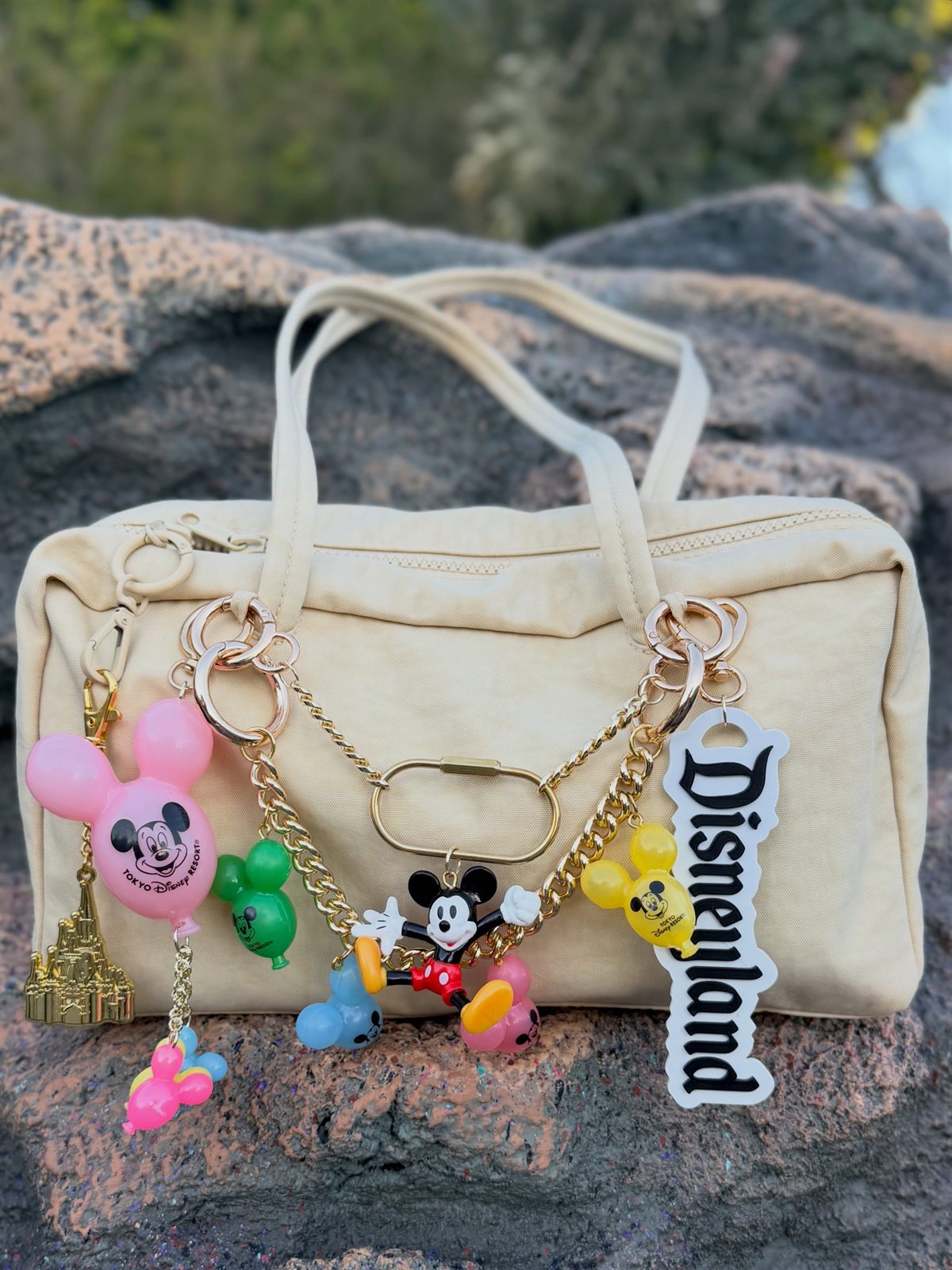 Cream bag with a gold chain, Mickey balloon charms and a Disneyland keychain